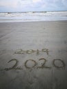 Happy new year 2020, lettering on the beach with wave and clear blue sea. Numbers 2020 year on the sea shore. Royalty Free Stock Photo