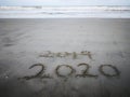 Happy new year 2020, lettering on the beach with wave and clear blue sea. Numbers 2020 year on the sea shore. Royalty Free Stock Photo