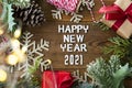 Happy New Year letters with red gift boxes, fir branches and Christmas decoration over wooden background. Top view Royalty Free Stock Photo