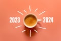 Happy new year and Merry Christmas 2024. Cup of coffee change and download 2023 to 2024 on orange background.