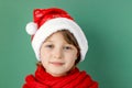 Happy new year and merry christmas. . Cute little caucasian girl in a santa hat and a red scarf on a green background Royalty Free Stock Photo