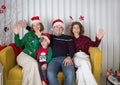 Happy New Year. Merry Christmas with family. joyful parents and children sit in room on couch in santa hats Royalty Free Stock Photo