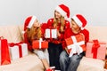 Happy family  a young mother with children  wearing santa claus hats  greets the New Year and gives each other Christmas gifts Royalty Free Stock Photo