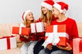 Happy family  a young mother with children  wearing santa claus hats  greets the New Year and gives each other Christmas gifts Royalty Free Stock Photo