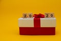 Happy New Year and Merry Christmas. Scrabble numbers with holiday present on yellow background. Bye 2020, welcomw 2021 Royalty Free Stock Photo
