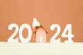 Happy New Year 2024 and Merry Christmas. Toy wooden house, white numbers 2024