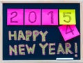 Happy New Year 2015 message hand written on blackboard, numbers stated on post-it notes, 2015 replacing 2014