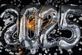 Happy new year 2025 metallic balloons with confetti and sparkler firework Bengal lights on dark black background