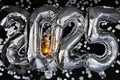 Happy new year 2025 metallic balloons with confetti and sparkler firework Bengal lights on dark black background