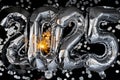 Happy new year 2025 metallic balloons with confetti and sparkler firework Bengal lights on dark black background