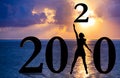 Happy new year mixed media card 2020- jumping woman silhouette over the sea as a part of 2020 number with sunset background Royalty Free Stock Photo
