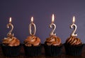 Happy New Year's Eve 2022 chocolate cupcakes decorated with gold burning candles Royalty Free Stock Photo