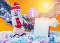 Happy New Year`s snowman in a red hat stands by a notepad. Orange background. Snowing. Royalty Free Stock Photo