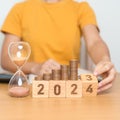 Happy New Year with sandglass and flipping 2023 change to 2024 block. Resolution, Goals, Plan, Action, Money Saving, Retirement