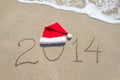 Happy new year 2014 with santa hat on sea beach sand with wave Royalty Free Stock Photo