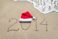 Happy new year 2014 with santa hat on sea beach sand with wave Royalty Free Stock Photo