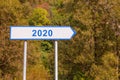 2020 happy New Year - signpost. White waywiser sign showing direction to year 2020. Nature background