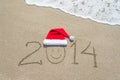 Happy new year 2014 with smiley face in santa hat on sandy beach Royalty Free Stock Photo