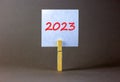 2023 happy new year symbol. Wooden clothespin, white sheet of paper with number 2023. Beautiful grey table grey background, copy Royalty Free Stock Photo