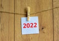 2022 happy new year symbol. Wooden clothespin, white sheet of paper with number 2022. Beautiful wooden background, copy space. Royalty Free Stock Photo