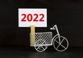 2022 happy new year symbol. Wooden clothespin, white sheet of paper with number 2022. Miniature bicycle model. Beautiful black Royalty Free Stock Photo