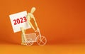 2023 happy new year symbol. Wooden clothespin, white sheet of paper with number 2023. Miniature bicycle model. Beautiful orange Royalty Free Stock Photo