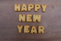 Happy New Year text composed with biscuit letters over a wooden board