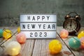 Happy New Year 2023 text on lightbox on wooden background