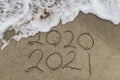 Happy New Year 2021 text on the sea beach. Handwritten inscription 2020 and 2021 on beautiful golden sand beach. Royalty Free Stock Photo