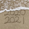 Happy New Year 2021 text on the sea beach. Handwritten inscription 2020 and 2021 on beautiful golden sand beach. Royalty Free Stock Photo