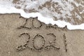 Happy New Year 2021 text on the sea beach. Handwritten inscription 2020 and 2021 on beautiful golden sand beach. Royalty Free Stock Photo