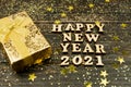 Happy new year 2021 text on wooden background with golden gift box. Festive greeting catd for holidays
