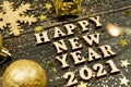 Happy new year 2021 text on wooden background surrounded golden christmas toys and fur tree branch. Festive greeting catd for