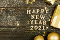 Happy new year 2021 text on wooden background surrounded golden christmas toys and fur tree branch. Festive greeting catd for