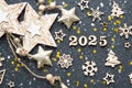 Happy New Year-wooden letters and the numbers 2025 on festive black background with sequins, stars, snow. Greetings, postcard.