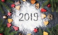 Happy New Year 2019 written on flour and Christmas Decorations Gingerbread cookies on dark stone background. New Year greeting car Royalty Free Stock Photo