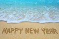 Happy new year written on sandy beach