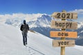 2021 happy new year written on a postsign with a hiker walking on the snow Royalty Free Stock Photo