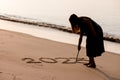 2023 Happy New Year, Young healthy woman writing 2023 on the sand beach at sunrise Royalty Free Stock Photo