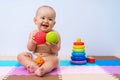 Happy newborn baby plays with rubber balls in the playroom. Development of hand motor skills in children Royalty Free Stock Photo