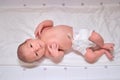 A happy newborn baby is smiling on a white changing table with a ruler for measuring height Royalty Free Stock Photo