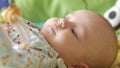 Happy newborn baby yawns closeup in colorfull bed The baby looks around and then smiles aywns. Concept of caring for