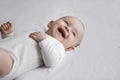 Happy newborn laughs lying resting on bed, close up shot