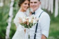 Happy newly married couple with boho style bouquet on wedding ceremony in forest. Selective focus on flowers Royalty Free Stock Photo