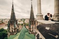 Happy newlywed. beautiful bride and stylish groom are kissing on the balcony of old gothic cathedral with panoramic city views Royalty Free Stock Photo