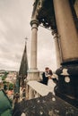 Happy newlywed. beautiful bride and stylish groom are kissing on the balcony of old gothic cathedral with panoramic city views Royalty Free Stock Photo