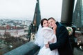 Happy newlywed bride and groom posing while embracing on the balcony of old gothic cathedral Royalty Free Stock Photo