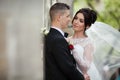 Happy newlywed brunette bride hugging handsome groom near old wa Royalty Free Stock Photo