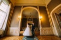 Happy newlywed couple dancing in bright hall with luxurious vintage interior