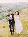 Happy newlywed couple is holding hands while walking in the mountains. Royalty Free Stock Photo